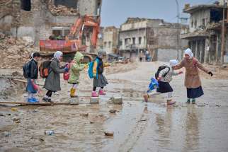 Girls navigate a muddy street Dec. 5 as they make their way to school amid the rubble of the Old City of Mosul, Iraq. when Islamic State controlled the city,most children did not attend school. 