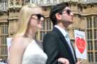 A man and woman dressed in wedding attire join a protest against a same-sex marriage bill outside the parliament building in London June 3, 2013. 