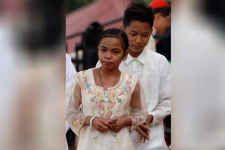 Glyzelle Palomar, 12, and Jun Chura, 14, two former street children, walk to their seats after greeting Pope Francis during a meeting with young people at the University of St. Thomas in Manila, Philippines, Jan. 18.