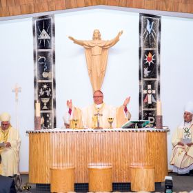 Moments after his ordination, Bishop Tony Krotki leads a packed Mary our Mother Church in the Eucharist. The Oblate missionary from Poland arrived in Canada in 1990 unable to speak English. Today he celebrates Mass and converses with the people of Nunavut in Inuktitut. The banners behind the altar are made from seal skin, while the crucifix to the right of the altar stands on a carved narwhal tusk sitting in a caribou antler base. At left is Ottawa Archbishop Terrence Prendergast, while Bishop Murray Chatlain of Mackenzie-Fort Smith is at the right.