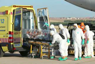 Health workers put Ebola patient, Father Miguel Pajares of Spain, into an ambulance Aug. 7 at a military air base in Madrid, after he was repatriated from Liberia for treatment. Ghana&#039;s bishops have urged the government to be extra vigilant in screening people who enter the country by sea for signs of Ebola.