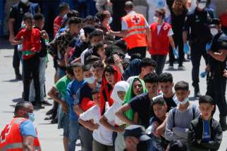 Moroccan minors line up at a facility prepared for them to rest and have food, after thousands of migrants swam across the Spanish-Moroccan border, in Ceuta, Spain, May 19, 2021. In a statement released May 18, the Spanish bishops&#039; conference expressed concern that migrants were being exploited after a sudden of influx of refugees into the Spanish territories of Ceuta and Melilla increased tensions between Spain and Morocco.