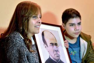 Veronica Stoberg of Santiago, Chile, alongside her son, Sebastian, holds a photo May 12 of Blessed Faustino Miguez, who is credited with her miraculous recovery after a complicated childbirth. The Spanish priest will be canonized by Pope Francis in October.