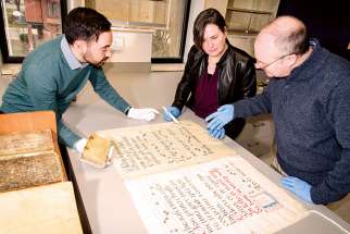 James Roussain, Sheril Hook and Noel McFerran (left to right) examine an illuminated text in the new conservation studio at the Kelly Library.