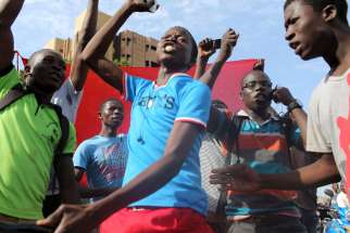Young men sing the Burkinabe national anthem as they protest the military coup in Ouagadougou, Burkina Faso, Sept. 22.