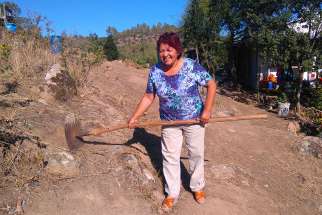 Ana Maria Araya Venegas from the Parish of Santa Rosa de Lavadero, Chile, displays the rake that helped save her house from recent forest fires in this March 13 photo. Prevention has helped parishes survive worst fires in Chile&#039;s history.