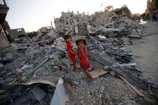 Two Palestinian sisters walk among the rubble of their destroyed home in the Gaza Strip Aug. 12. A senior Catholic aid official said humanitarians are &quot;trying to pick of the pieces&quot; of Gaza&#039;s badly destroyed infrastructure, hoping that the truce between Israel and the militant Hamas will hold.
