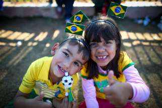 Young Brazilian fans pose for a photo outside the Arena Corinthians stadium in Sao Paulo June 11. At the Vatican, Pope Francis told fans, players and organizers the World Cup should be a celebration of solidarity and peace.