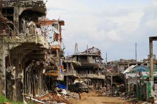 A military truck maneuvers next to destroyed buildings in the war-torn city of Marawi, Philippines. There will be no Holy Week observance this year in Marawi almost a year after extremist gunmen occupied the southern Philippine city. 