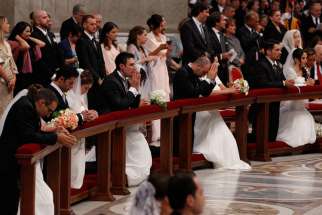 Newly married couples kneel as Pope Francis celebrates the marriage rite for 20 couples during a Mass in St. Peter&#039;s Basilica at the Vatican Sept. 14. 