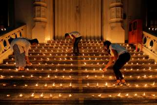 Young people light candles near the closed door of a church in Colombo, Sri Lanka, April 28, 2019, during a vigil in memory of the victims of a string of suicide bomb attacks across the island on Easter . 
