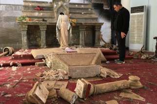 A Catholic church destroyed by Islamic State militants in Karamdes, Iraq, is examined by a priest March 6, 2018. The genocide conducted by the Islamic State against Christian communities in Iraq and Syria has turned into continued harassment by Iran-backed militias and shows no signs of abating soon, said speakers at a Sept. 26, 2019, hearing in Washington.