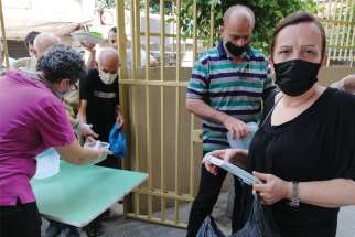 At the Socio-Medical Intercommunity Dispensary in the Naba neighbourhood of Beirut, people receive a hot meal to take back to their homes Sept. 2. The centre experienced considerable damage from the explosion in Beirut’s port area Aug. 4.