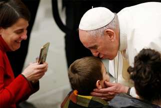 Pope Francis greets a boy as he meets the sick and disabled during his general audience in Paul VI hall at the Vatican Feb. 20, 2019. 