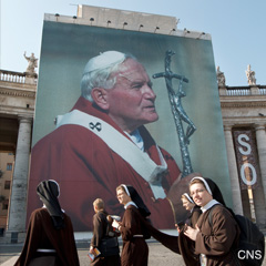 Franciscan nuns from Bologna, Italy, walk past a giant image of Pope John Paul II in St. Peter's Square at the Vatican April 28.