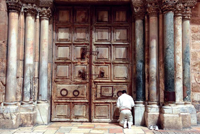 A Christian kneels in prayer outside the locked door of the Church of the Holy Sepulcher in Jerusalem’s Old City on Palm Sunday. The Holy Land tourism industry is expecting to have a bounce back year in 2022.