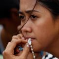 A woman holds a rosary as she waits to board a military evacuation flight from the typhoon-battered city of Tacloban, Philippines, Nov. 13. Hundreds of thousands of people in Leyte province had been displaced by Typhoon Haiyan, one of the worst storms to hit land.