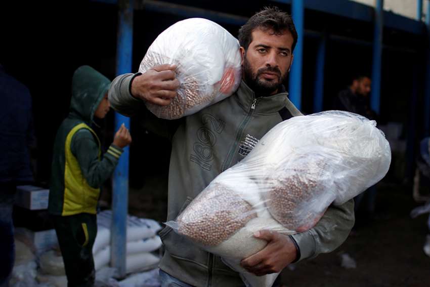 A Palestinian carries food supplies at a United Nations food distribution center in the Al-Shati refugee camp in Gaza City Jan. 15.