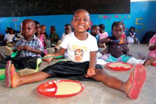 Children in a Malawi school sit down for a meal.