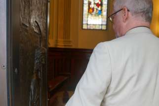 Ordinariate priest Fr. John Hodgins, of St. Thomas More Catholic Church in Toronto, grasps the outstretched hand sculpted on the Holy Door in the Cathedral-Basilica of Notre Dame in Quebec City.
