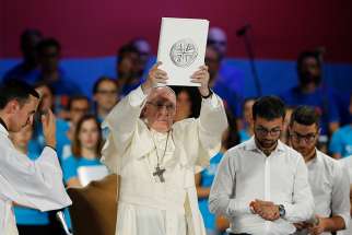 Pope Francis raises the Book of the Gospels during an evening meeting with Italian young adults at the Circus Maximus in Rome Aug. 11. 