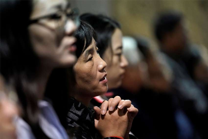 A woman is seen praying during Mass at a church in Beijing Sept. 29, 2018. Bishop Joseph Zhang Weizhu of Xinxiang -- a Vatican-approved Chinese prelate --remains in detention more than one year after his arrest, accused of violating the communist country&#039;s regulations on religious affairs.