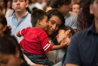 A woman holds onto her children during a special Mass in Los Angeles honouring immigrants.  