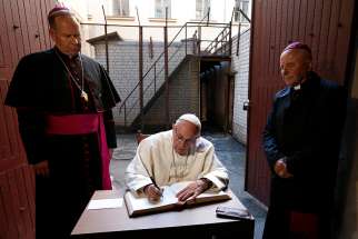  Pope Francis signs a guest book after visiting the Museum of Occupations and Freedom Fights in Vilnius, Lithuania, Sept. 23. At left is Archbishop Gintaras Grusas of Vilnius. 