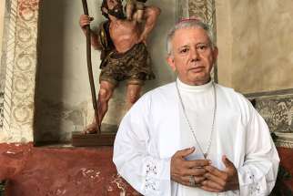  Bishop Ramon Castro Castro of Cuernavaca, Mexico, poses March 26 in the Assumption of Mary Cathedral in front of an image of St. Christopher from the colonial period.