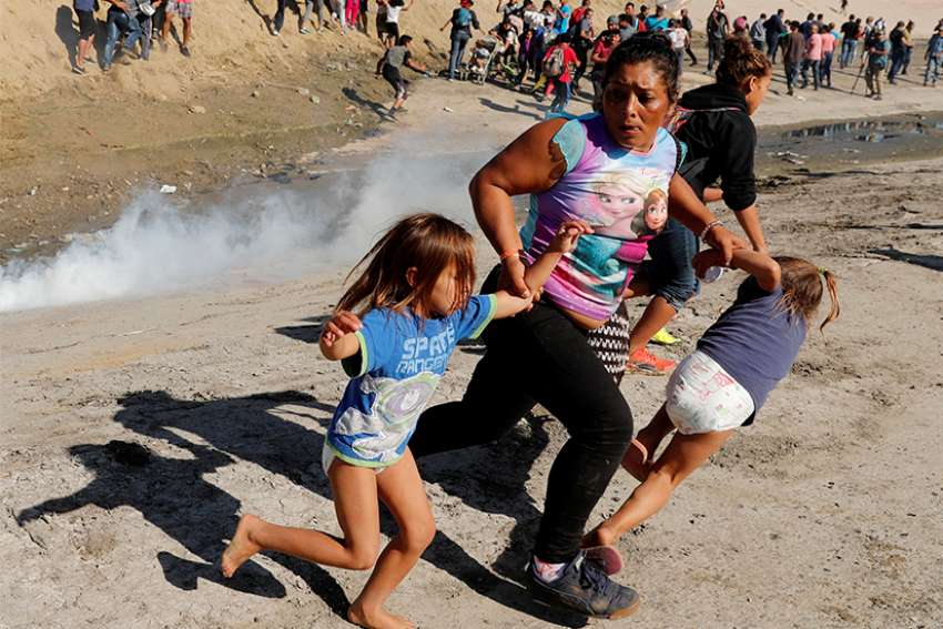A Honduran migrant family who are part of a caravan trying to reach the U.S. run from tear gas released by U.S. border patrol near Nov. 25 the fence between Mexico and the United States in Tijuana, Mexico. 