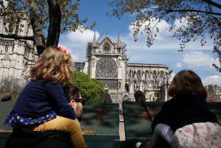 A family looks at Notre Dame Cathedral April 17, 2019, two days after a fire destroyed much of the church&#039;s wooden structure.