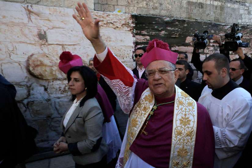 Latin Patriarch Fouad Twal of Jerusalem waves upon his arrival to attend Christmas celebrations in Bethlehem, West Bank, Dec. 24.