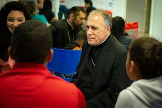 Cardinal Daniel N. DiNardo of Galveston-Houston, president of the U.S. Conference of Catholic Bishops, listens to immigrants recently released from U.S. custody July 1 at a Catholic Charities-run respite center in McAllen, Texas. A delegation of U.S. bishops traveled to the Diocese of Brownsville, Texas, to learn more about the detention of immigrants, mostly Central Americans, at the U.S.-Mexico border.