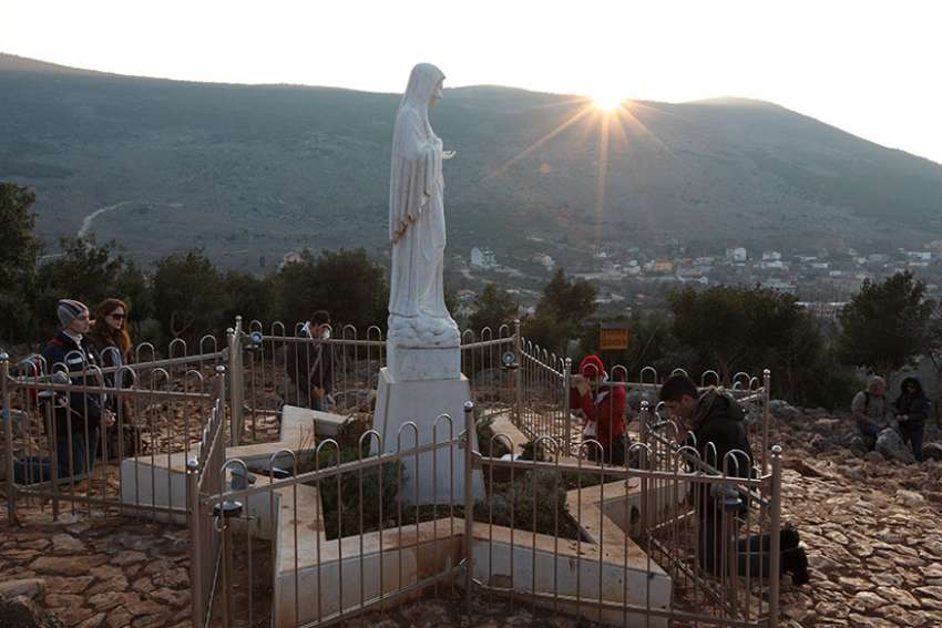 Pilgrims pray around a statue of Mary on Apparition Hill in Medjugorje, Bosnia-Herzegovina, in this Feb. 26, 2011, file photo.