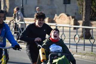 Jose Manuel Roás Triviño pushes his son Pablo Roas in a specially designed wheelchair when he runs marathons.