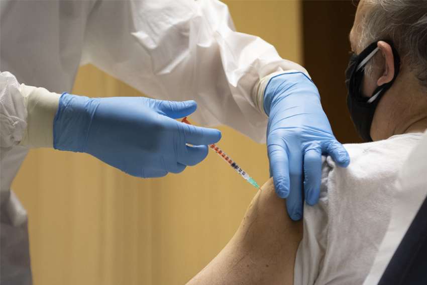 A man receives the first dose of the COVID-19 vaccine in the atrium of the Paul VI hall at the Vatican in this Jan. 20, 2021, file photo. A variety of sanctions have been issued by the head of the commission governing Vatican City State for citizens, residents and personnel who fail to follow current COVID-19 measures. The sanctions cover employees who refuse vaccination.