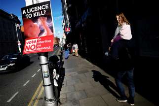 People walk past a pro-life poster in Dublin May 7. Ireland votes May 25 on whether the right to life of the unborn should continue to be enshrined in the constitution.