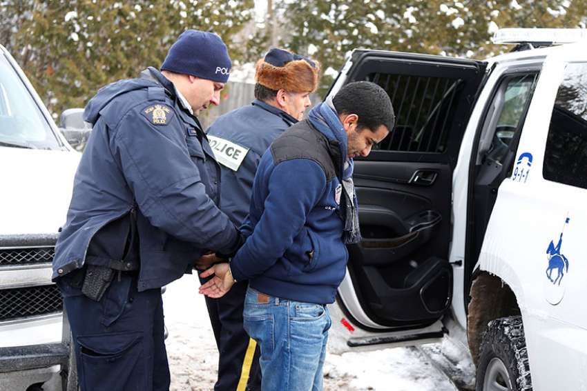 A man who told police he was from Mauritania is taken into custody Feb. 14 by Royal Canadian Mounted Police officers after walking across the U.S.-Canada border into Quebec.