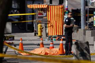 A police officer stands next to a victim at the site where a van struck multiple people at a major intersection in Toronto&#039;s northern suburbs April 23. At least 10 people were dead and 15 were injured, authorities said. 