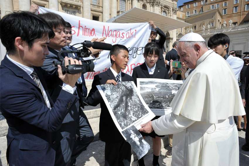 Pope Francis examines photos of the 1945 atomic bombing of Japan as he greets members of the Hiroshima and Nagasaki Youth Peace Messengers this past June.