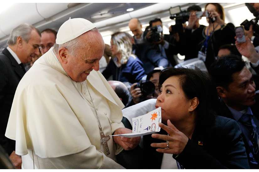 Pope Francis accepts a card from Filipino reporter Lynda Jumilla Abalos of ABSCBN television while greeting media aboard the papal flight to Colombo, Sri Lanka, Jan. 12. The card was made by the children of the journalist to welcome the pope to the Philippines.