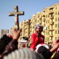 A demonstrator holds up a crucifix and a Quran during a protest at Tahrir square in Cairo. Religious communities can help pro-democracy movements in the Middle East and North Africa by upholding human dignity, says a Vatican official.