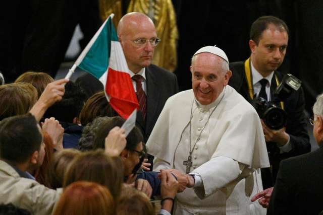 Italy&#039;s flag is seen as Pope Francis greets people at Rome&#039;s Church of St. Gregory VII March 21 after a prayer service for victims of the Mafia.