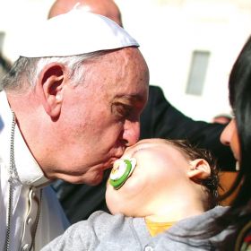 Pope Francis kisses a baby after his weekly audience Nov. 6. In his first extensive piece of writing as Pope, Francis lays out a vision of the Catholic Church dedicated to evangelization, with a focus on the poorest and most vulnerable, including the aged and unborn.