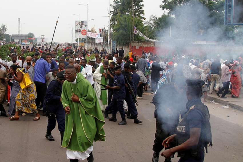 A priest runs as riot police fire tear gas canisters to disperse demonstrators during a protest organized by Catholic activists in Kinshasa, Congo. At least six people were killed during demonstrations across the country against delayed elections and Congolese President Joseph Kabila. 