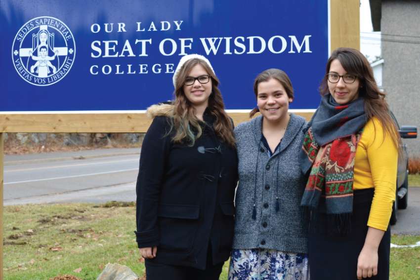 Elizabeth Jordan, Magdalene Vandenburg and Emma White proudly pose with SWC’s new sign. Before the degree accreditation, the school was called Our Lady Seat of Wisdom Academy.