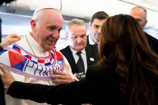 Pope Francis tries on a scarf given to him by a reporter from Panama Jan. 23, 2019, aboard his flight from Rome to Panama for World Youth Day.