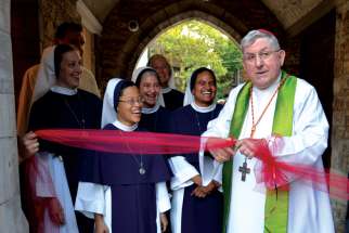 Cardinal Thomas Collins cuts the ribbon to open the new Sisters of Life Centre adjacent to St. Peter’s Church in downtown Toronto as members of the Sisters of Life look on. 
