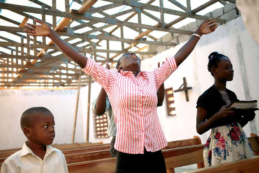 A woman prays in a roofless church in Torbeck, Haiti, Oct. 9 after Hurricane Matthew swept through the island nation.