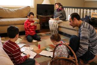 Syrian refugees Ahmed Al Kango and his wife, Sahar, help their children learn English Feb. 7 in their home in Elkhorn, Neb. Pictured from left, the children are Mohamad, Ghaith and Abdulrazzaq.